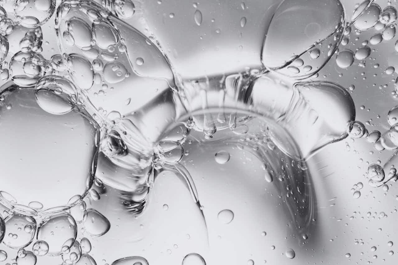 Macro image of a clear gel texture with trapped air bubbles, typical for care products