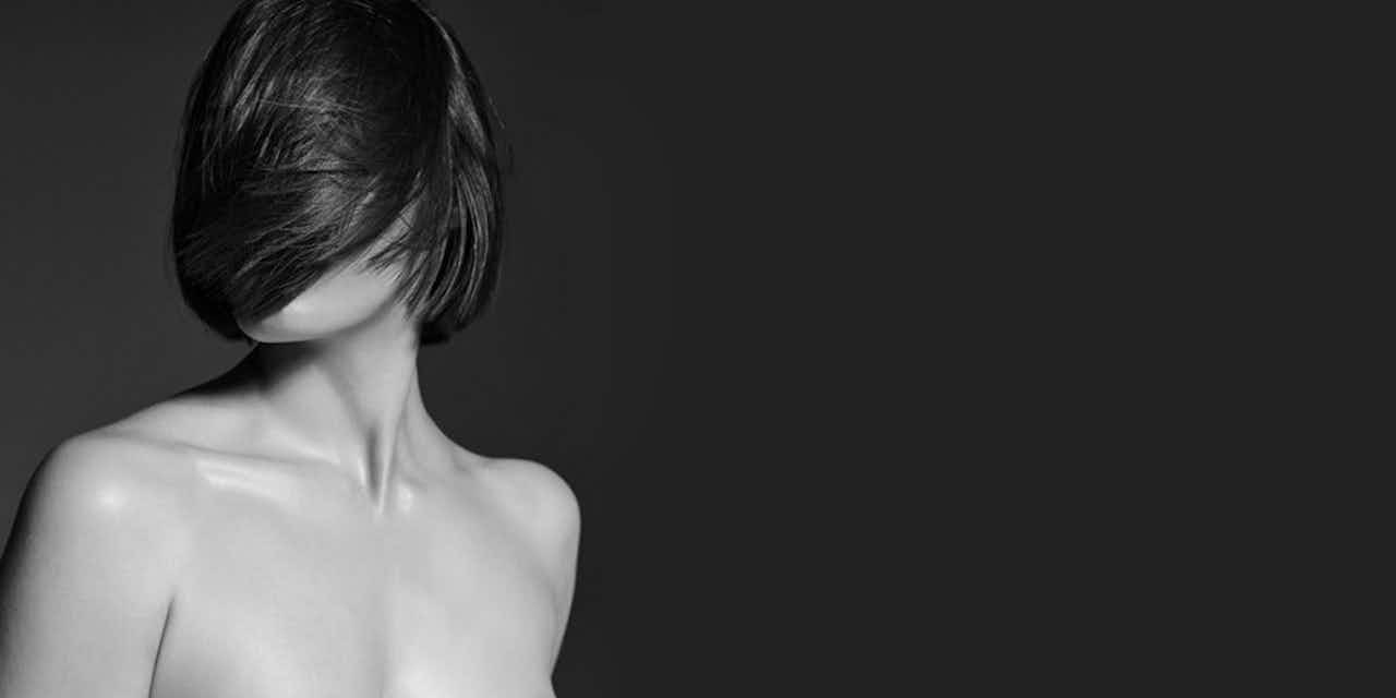 Image detail in black and white of a woman from head to shoulders with blown hair over her face